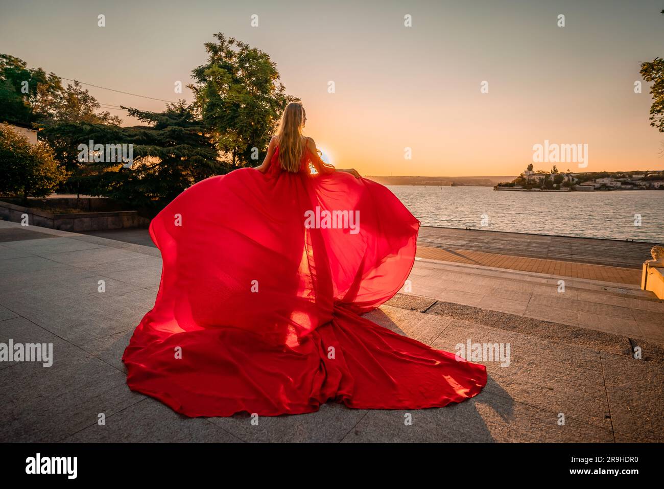 Sunrise red dress. A woman in a long red dress against the backdrop of ...