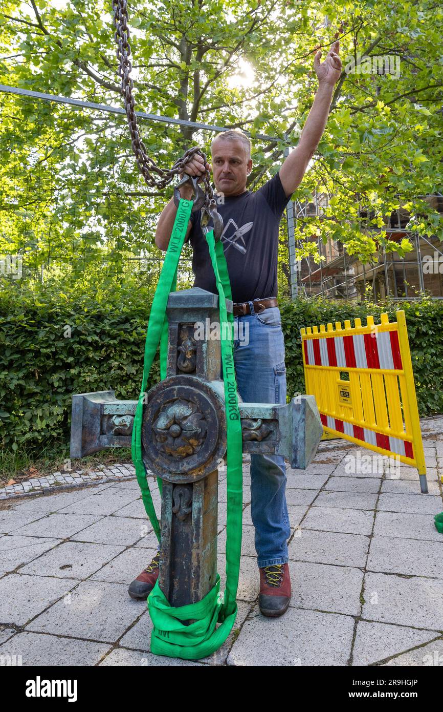 27 June 2023, Saxony, Dresden: Master plumber Gero Zenker prepares the 50 kg cross for the northern steeple of the Trinity Church with loops and gives the signal for the crane operator to pull it up. The 120 kg base has already been mounted on the tower, so that now all three towers of the church shine again. Photo: Daniel Schäfer/dpa Stock Photo