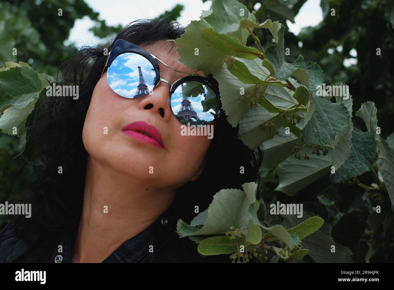 Oversized round mirror sunglasses reflecting the Eifel Tour, worn by a fashionable Asian woman in Paris Stock Photo