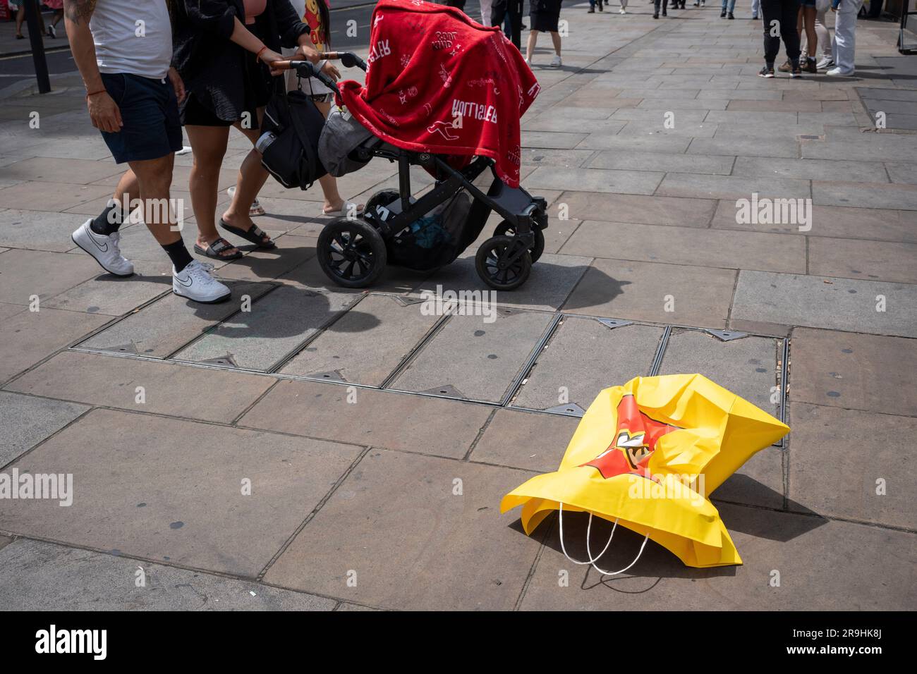 Passers-by walk near a discarded Lego shopping bag in Coventry Street, Westminster, on 26th June, in London, England. Stock Photo