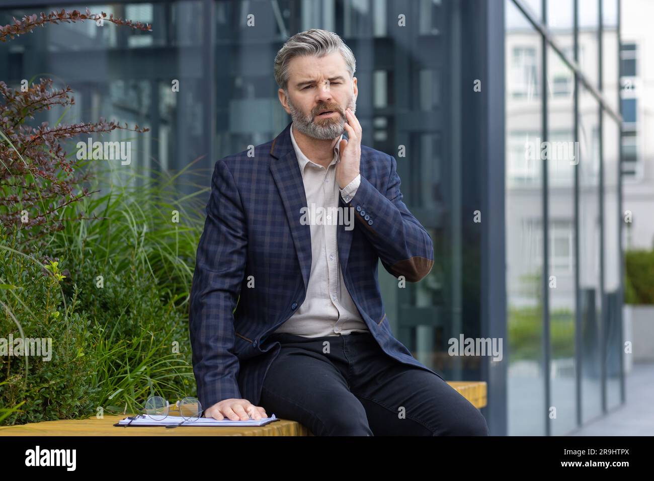 Toothache, mature adult male businessman sitting outside office ...