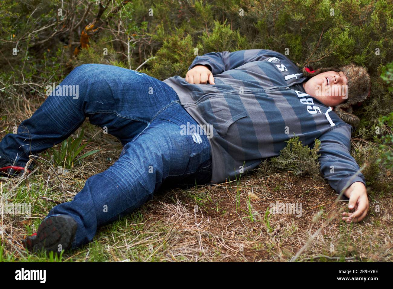 Drunk, sleeping and hangover with a plus size man lying outdoor on the grass or ground after a party. Festival, alcohol and tired with a young male Stock Photo