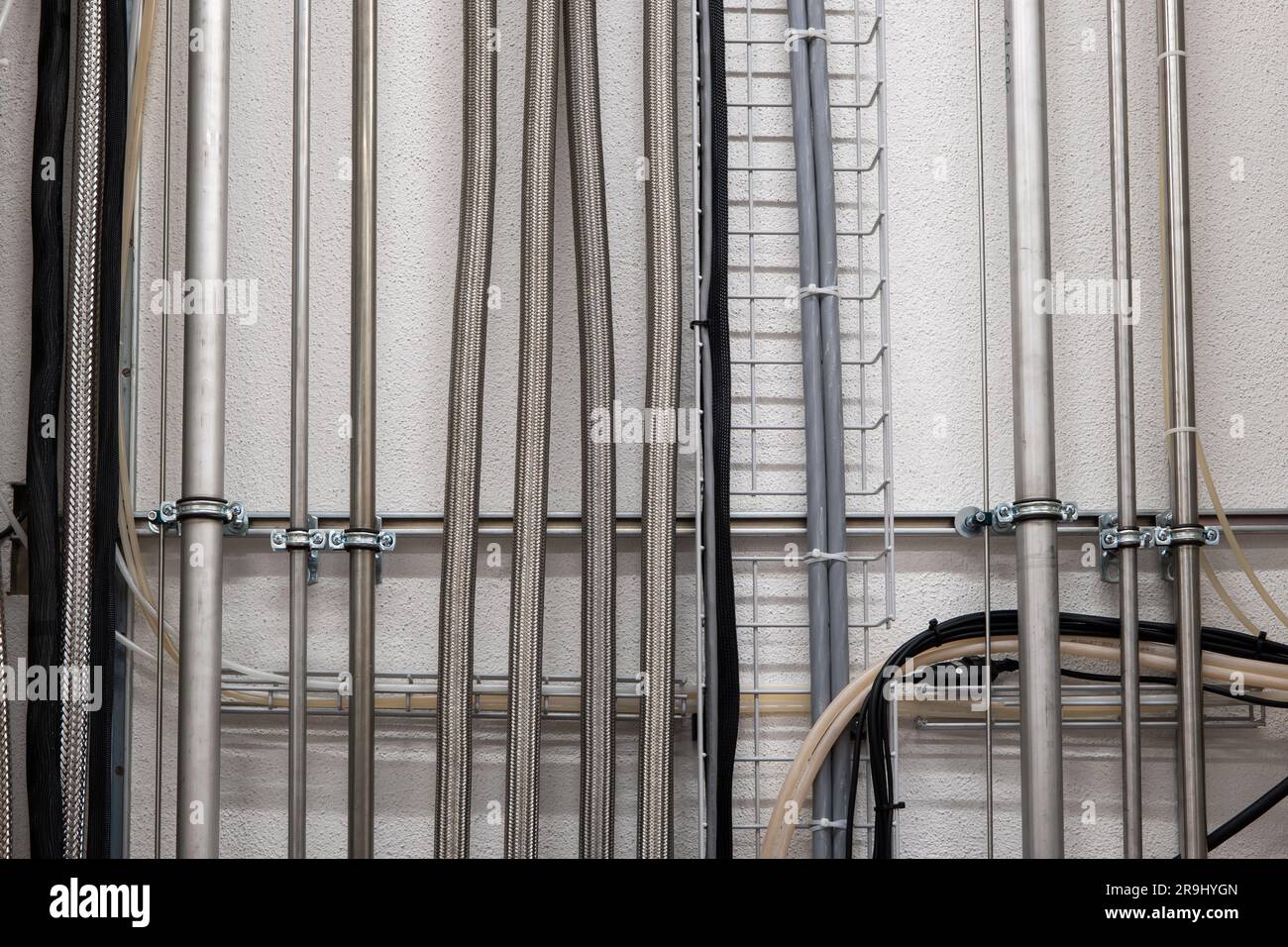 Vertical wall mounted pipes and electrical cables in an industrial