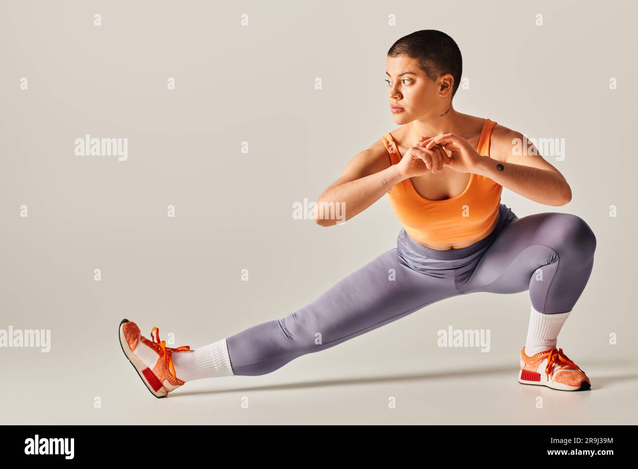 self-esteem, body positivity, flexible and short haired woman stretching  legs on grey background, curvy fitness model in sportswear, athletic and  conf Stock Photo - Alamy