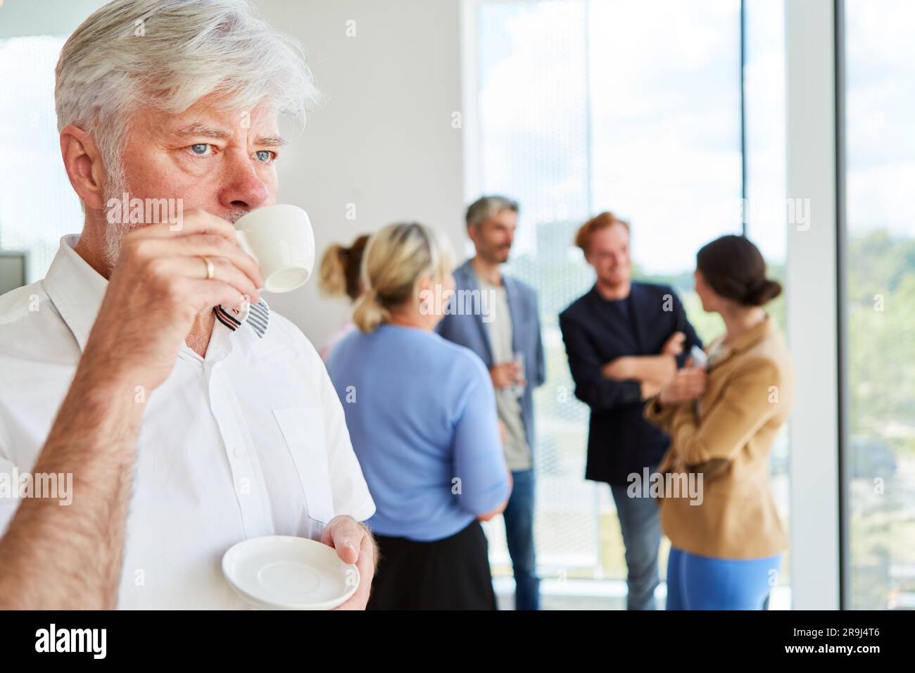 Thoughtful senior businessman with white hair drinking coffee Stock Photo