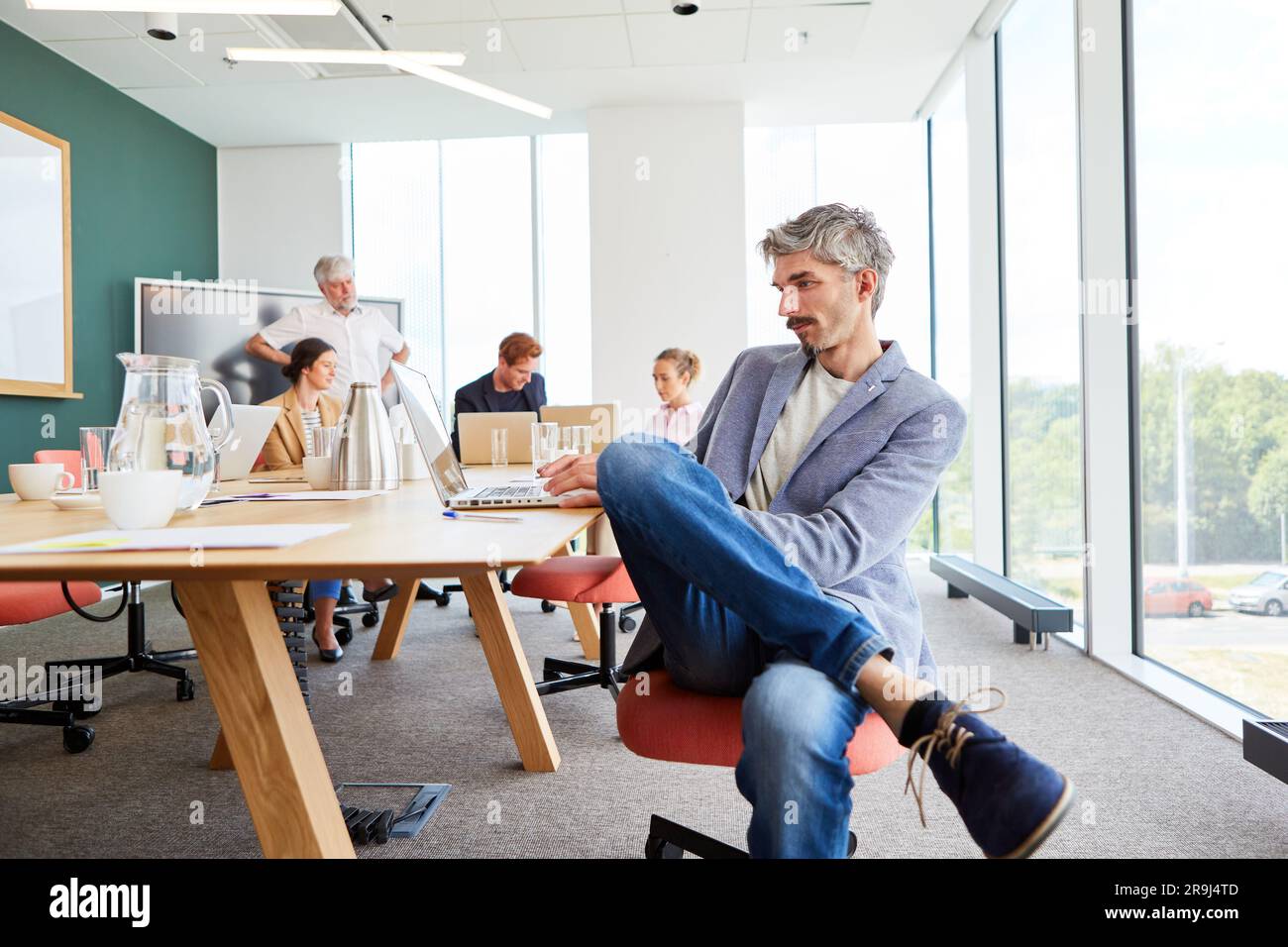 Businessman using laptop sitting at table in conference room Stock Photo