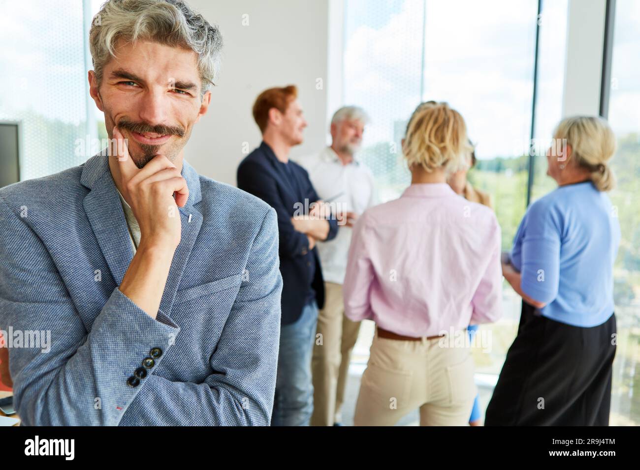 Smiling businessman with mustache wearing blazer at workplace Stock Photo