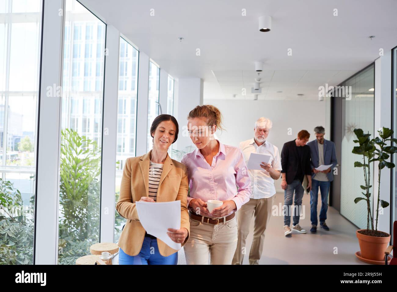 Female entrepreneurs discussing over documents while walking in corridor Stock Photo
