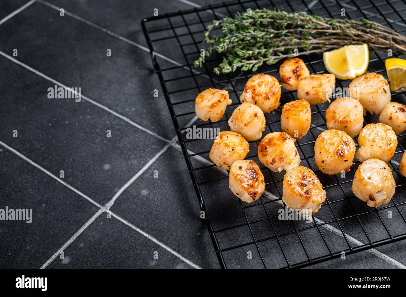 Grilled Scallops fillets on a rack. Black background. Top view. Copy space. Stock Photo