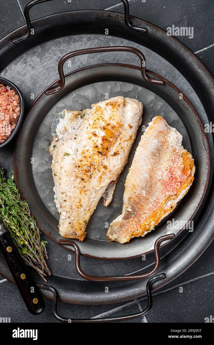 Roasted ocean red perch fillet with olive oil, thyme and spices. Black background. Top view. Stock Photo