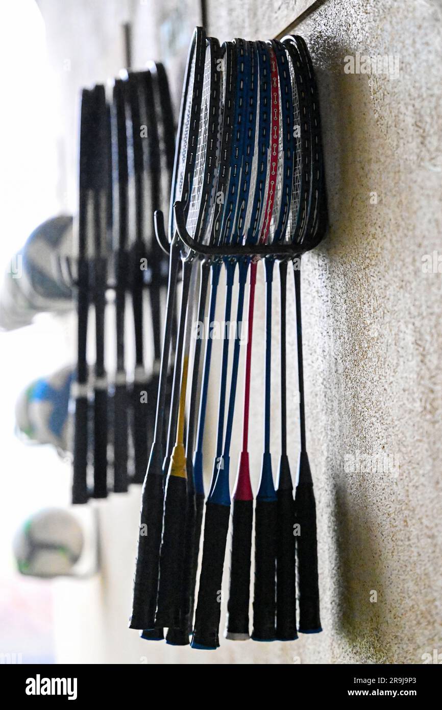 A closeup of badminton rackets of vibrant colors suspended from a wall-mounted hook Stock Photo