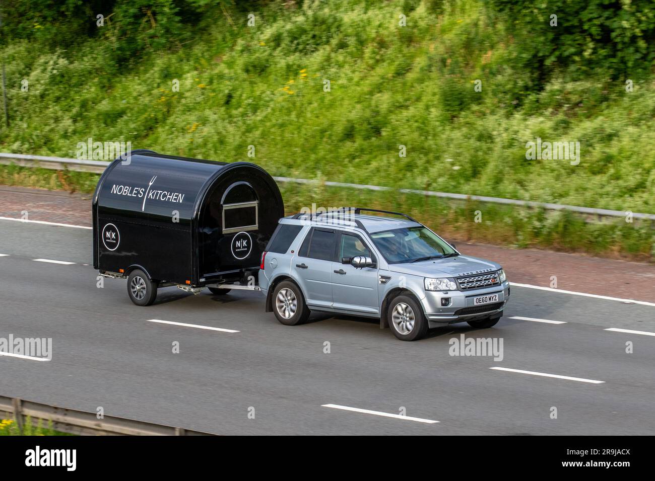 Nobles Kitchen catering trailer towed by 2011 Land Rover silver Freelander Xs Sd4 Auto SD4 190 Commandshift Auto Car SUV Diesel 2179 cc; travelling at speed on the M6 motorway in Greater Manchester, UK Stock Photo
