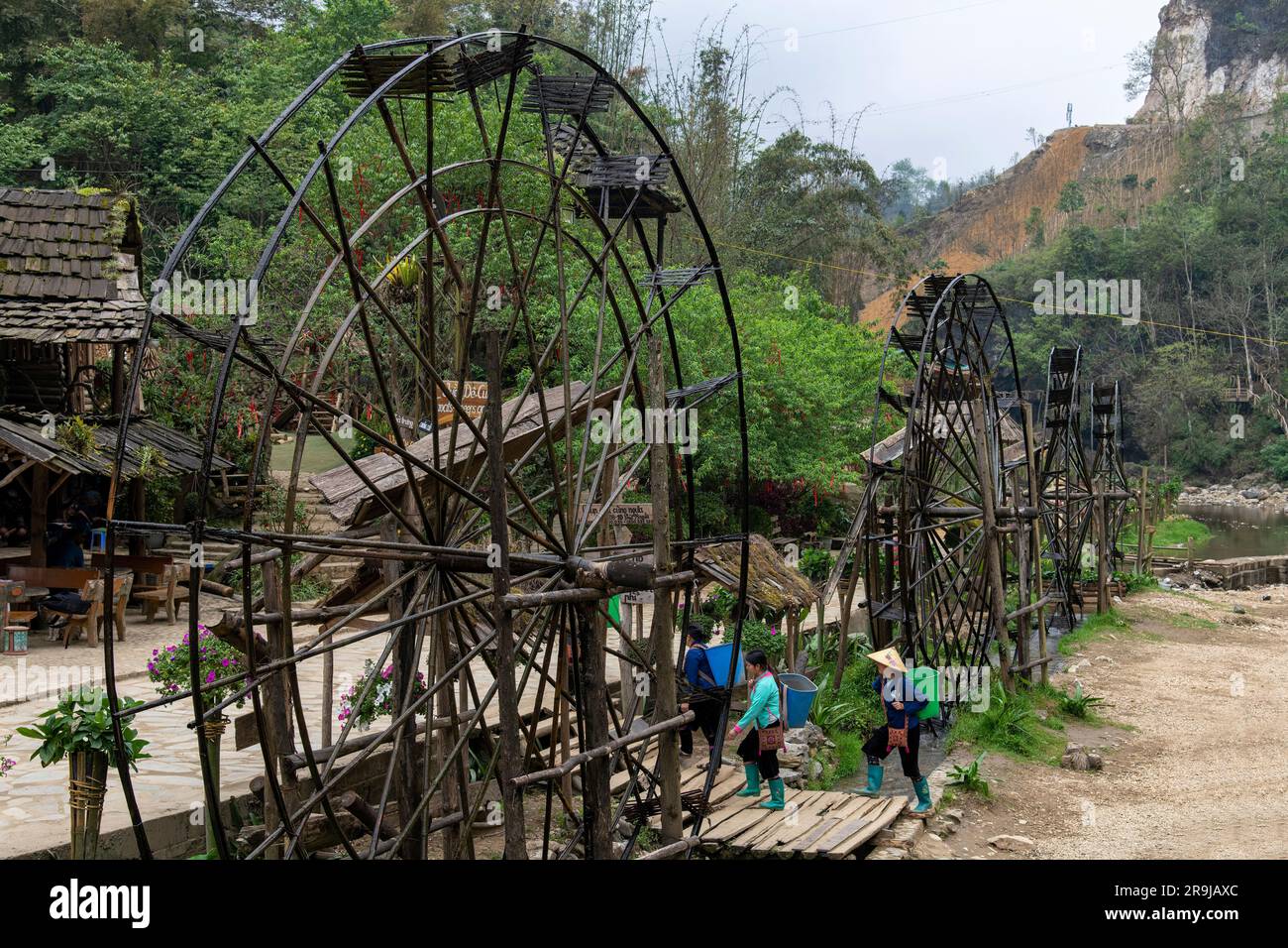 Cat Cat Village, Sapa, Vietnam-April 2023; Water wheels for power generation and made of bamboo and vines lined up in the village with some locals pas Stock Photo