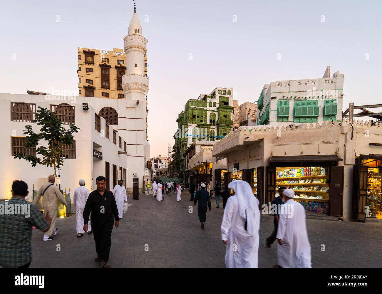 Jeddah, Saudi Arabia - People dressed in traditional cloth walk in front of the Al Ma'amar Mosque in Jeddah old town of Al-Balad in Saudi Arabia Stock Photo
