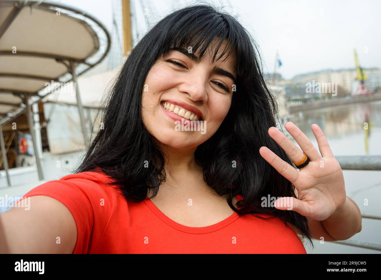 Selfie portrait of young latin woman of venezuelan ethnicity dressed in red, with black hair, smiling happy outdoors, tourist in the city of Buenos Ai Stock Photo