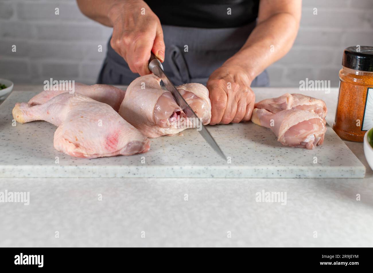 Cutting or carving raw chicken leg into shank and drumstick. Part of a series Stock Photo