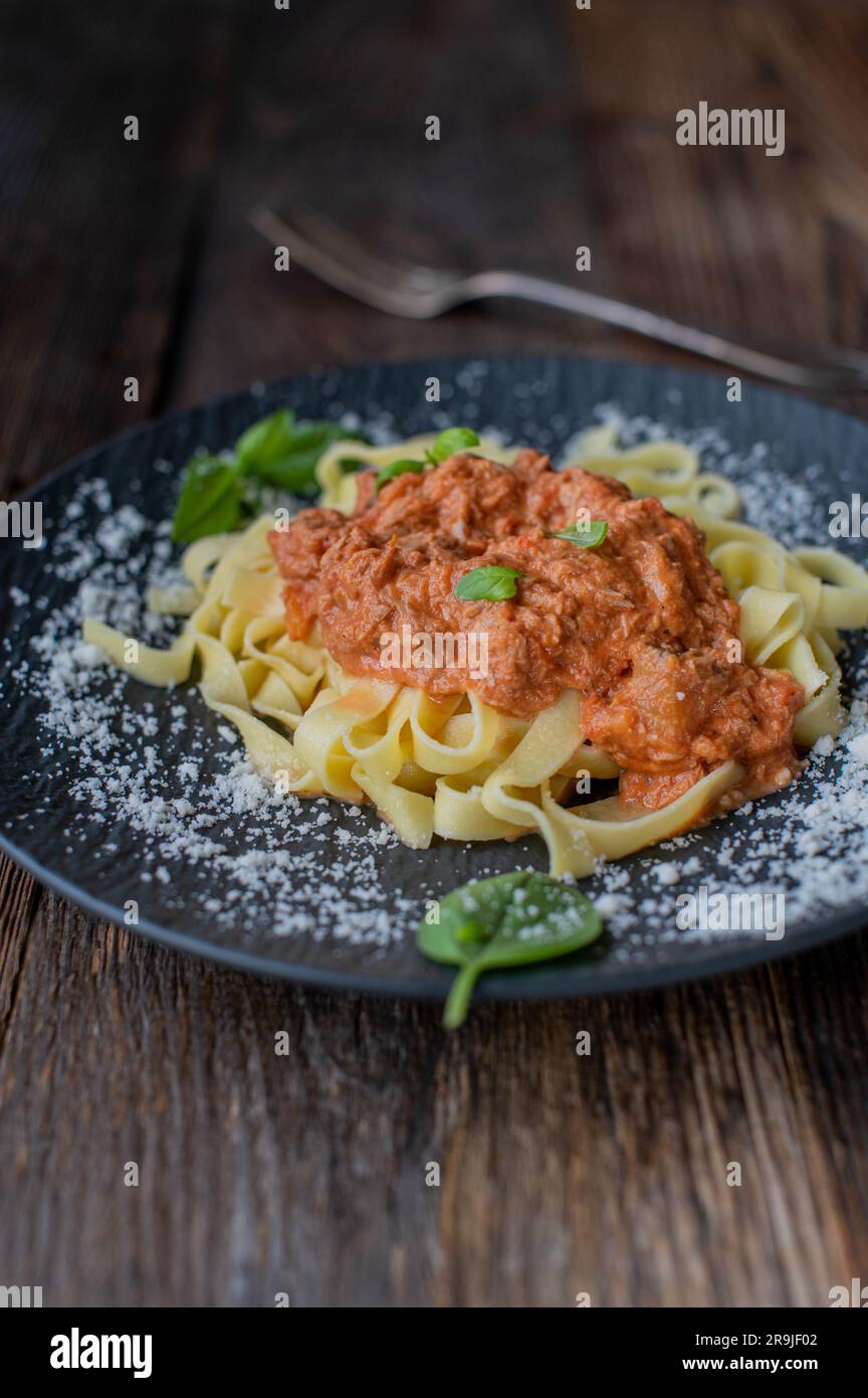 Tagliatelle noodles with tuna tomato sauce and grated parmesan cheese on a plate Stock Photo