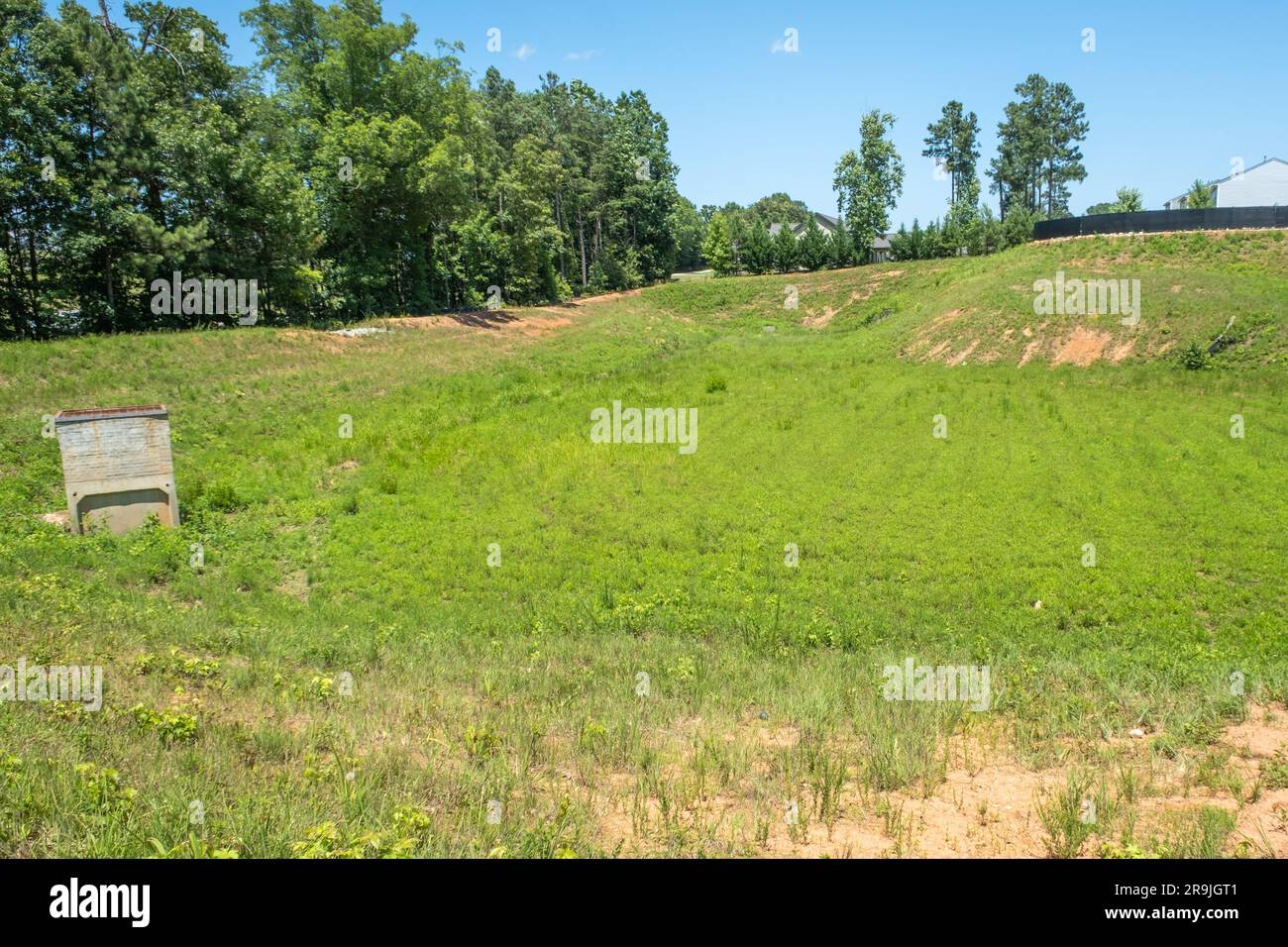 Large drainage ditch lined with grass and weeds behind a subdivision Stock Photo