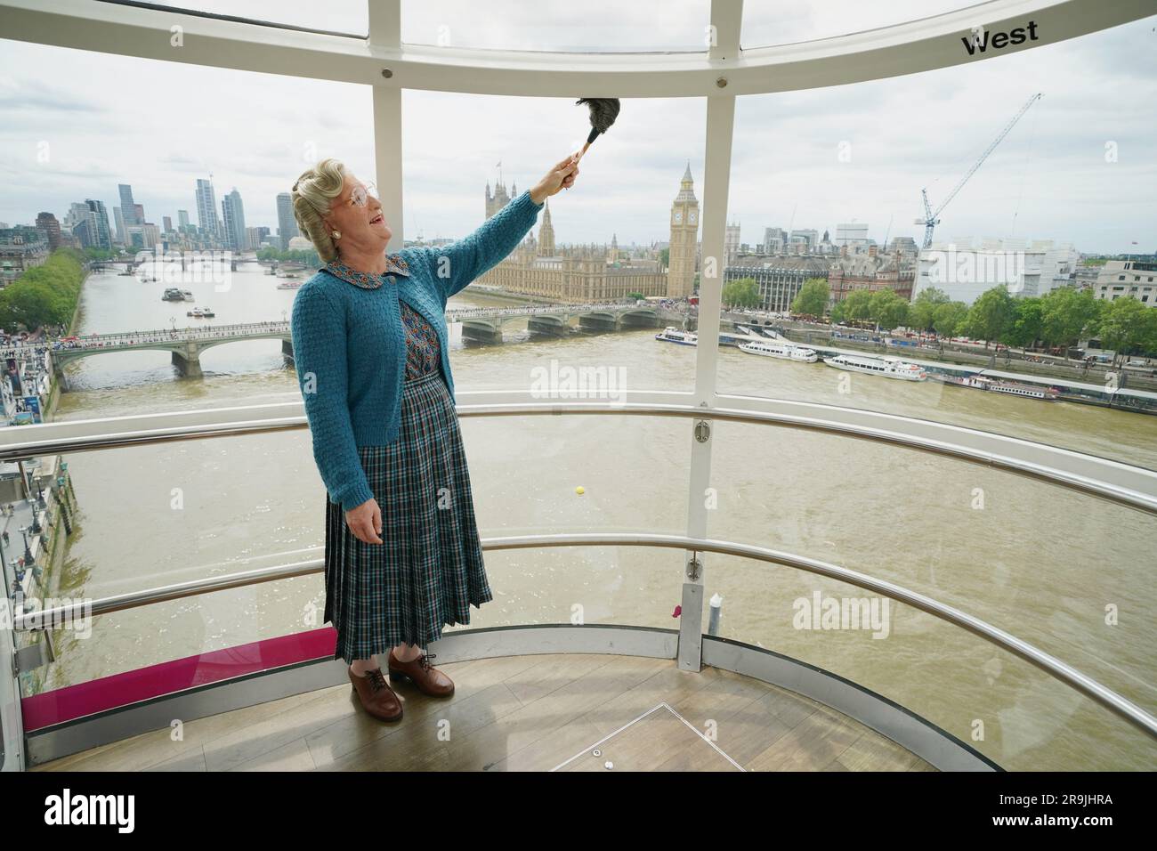 Mrs Doubtfire, played by Gabriel Vick in the musical production in London's West End, gives a pod on the lastminute.com London Eye a clean - reenacting the iconic cleaning scene from the 1993 movie. The comedy musical based on the original film is currently playing at the Shaftesbury Theatre in London. Picture date: Tuesday June 27, 2023. Stock Photo