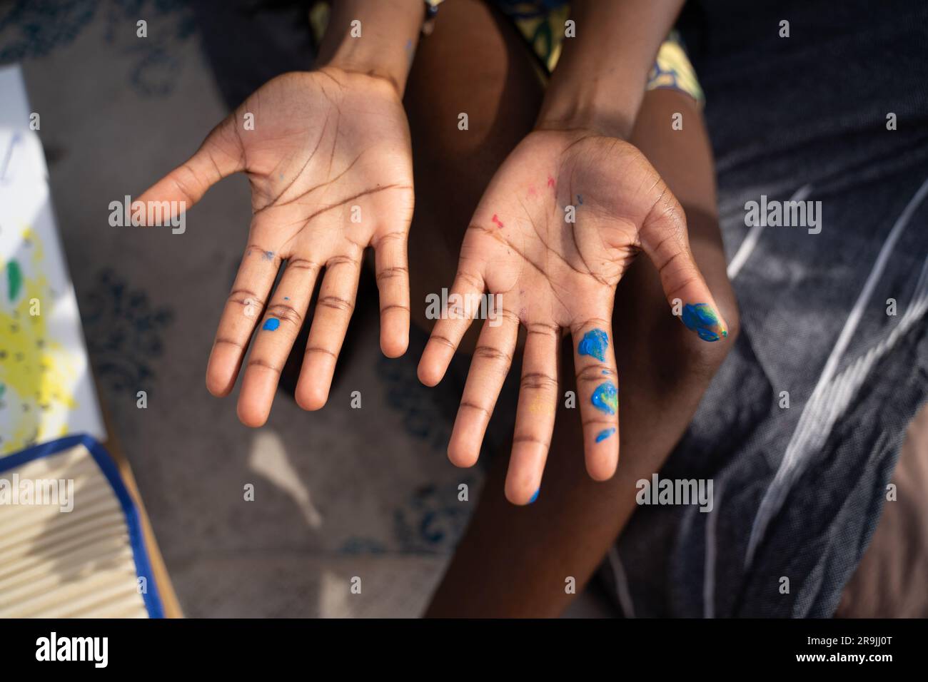 From above of crop anonymous female showing palms with blue paint while ...
