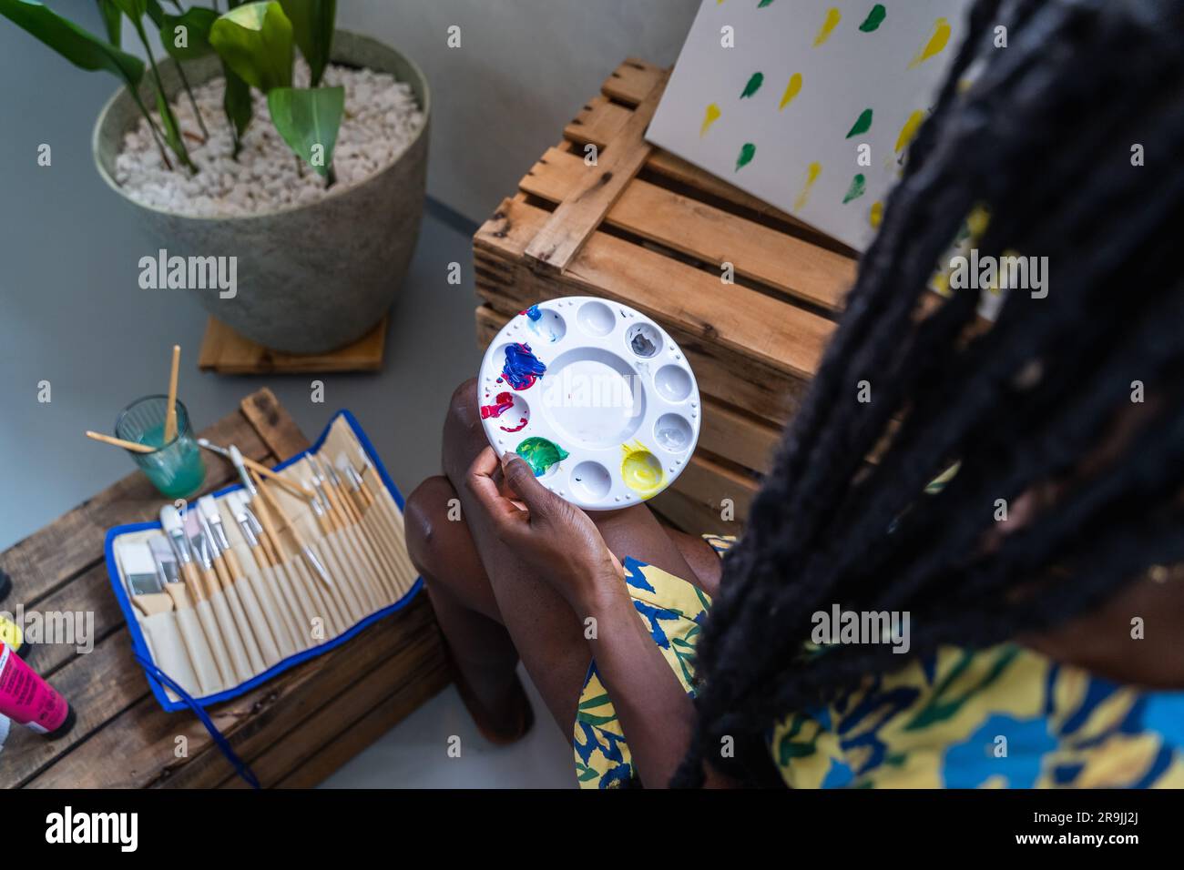 High angle of crop anonymous female painter with long deadlocks holding ...