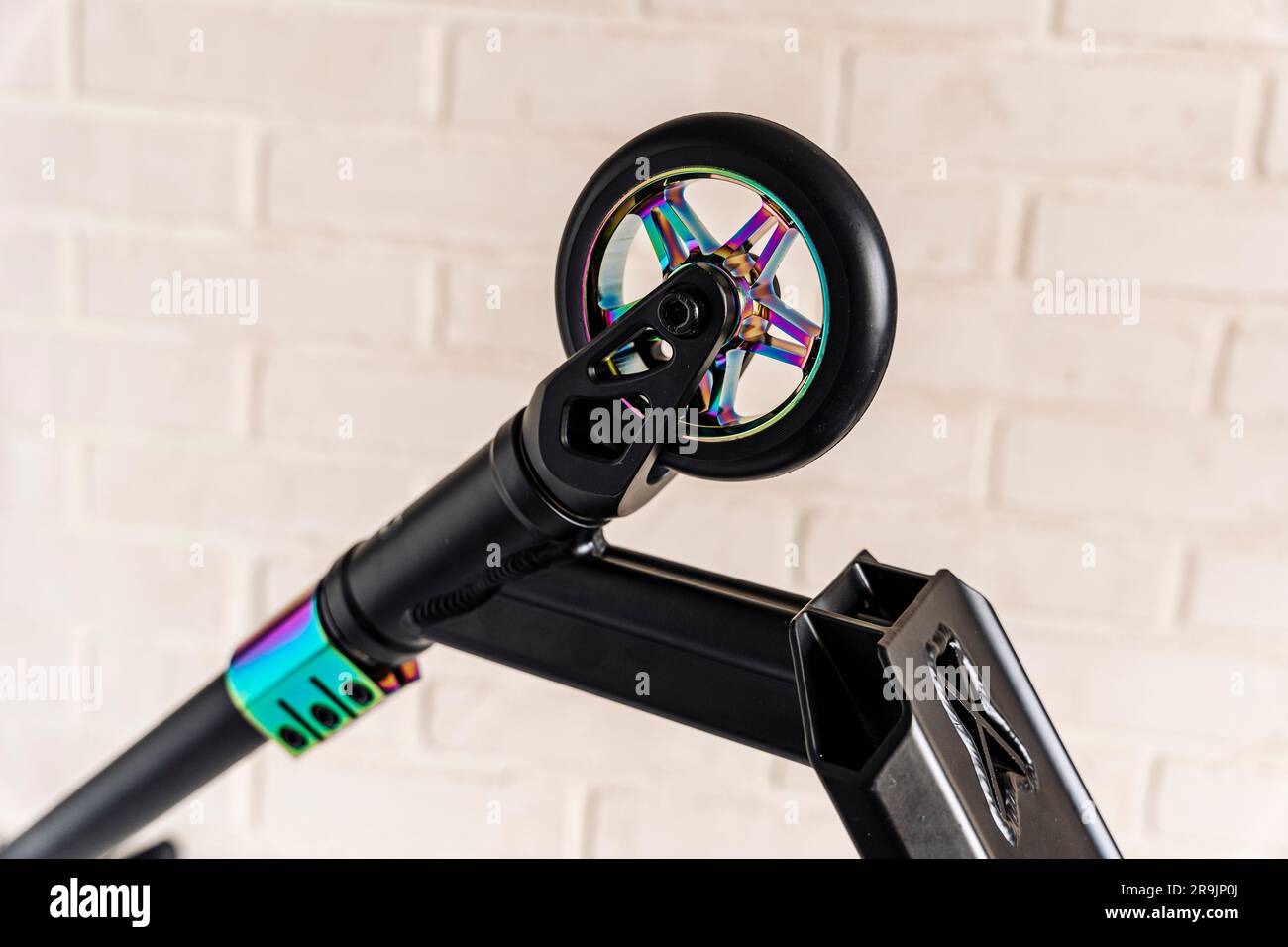 Front view of a stunt scooter with rainbowcolored wheels. equipment