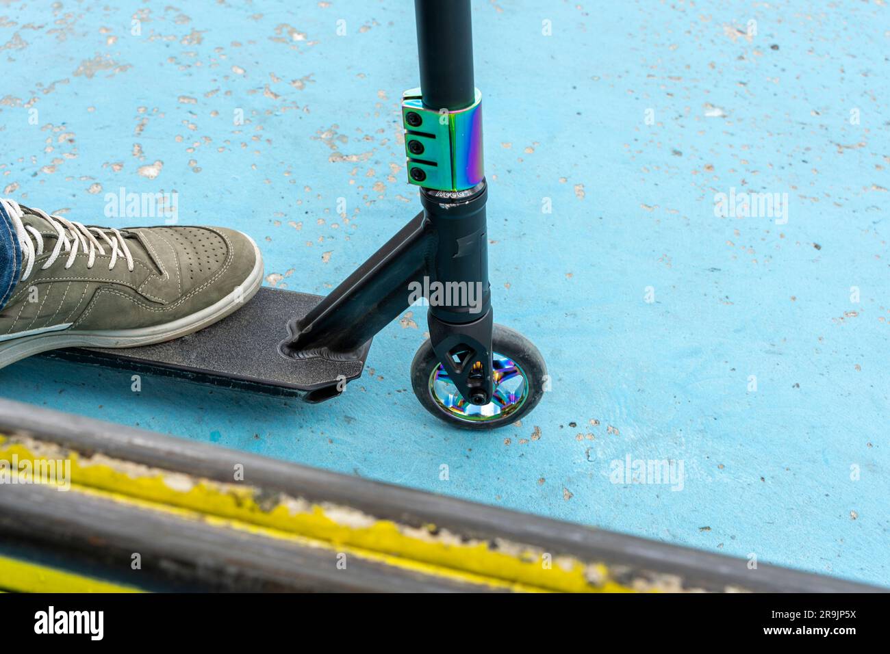 Rider boy legs close up in sneakers on stunt scooter on the skate park