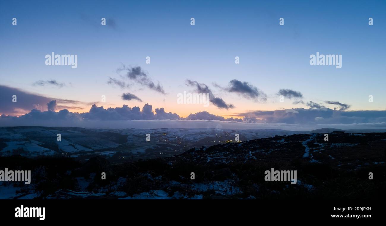 The photograph captures view from Bamford Edge during winter after the sunset. The sky is adorned with hues of blue and purple, creating a serene and Stock Photo