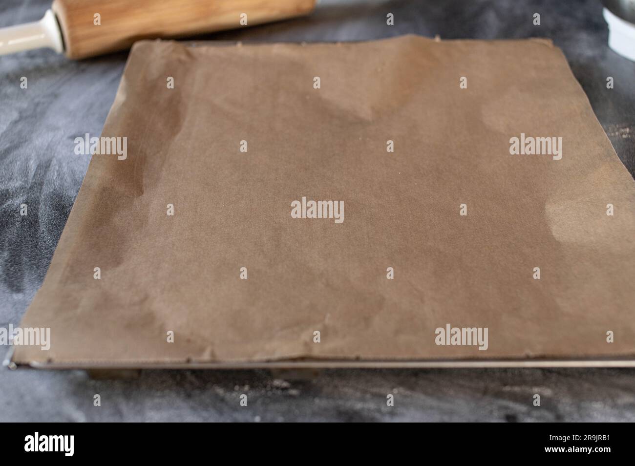 Empty baking tray with rolling pin isolated on a floured table Stock Photo