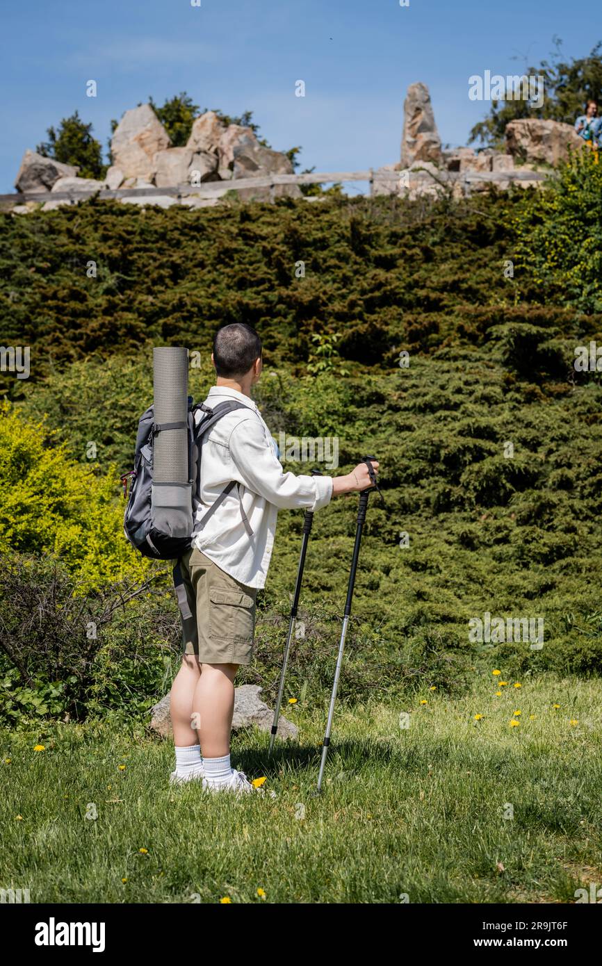 Back view of young short haired female hiker with backpack and travel ...