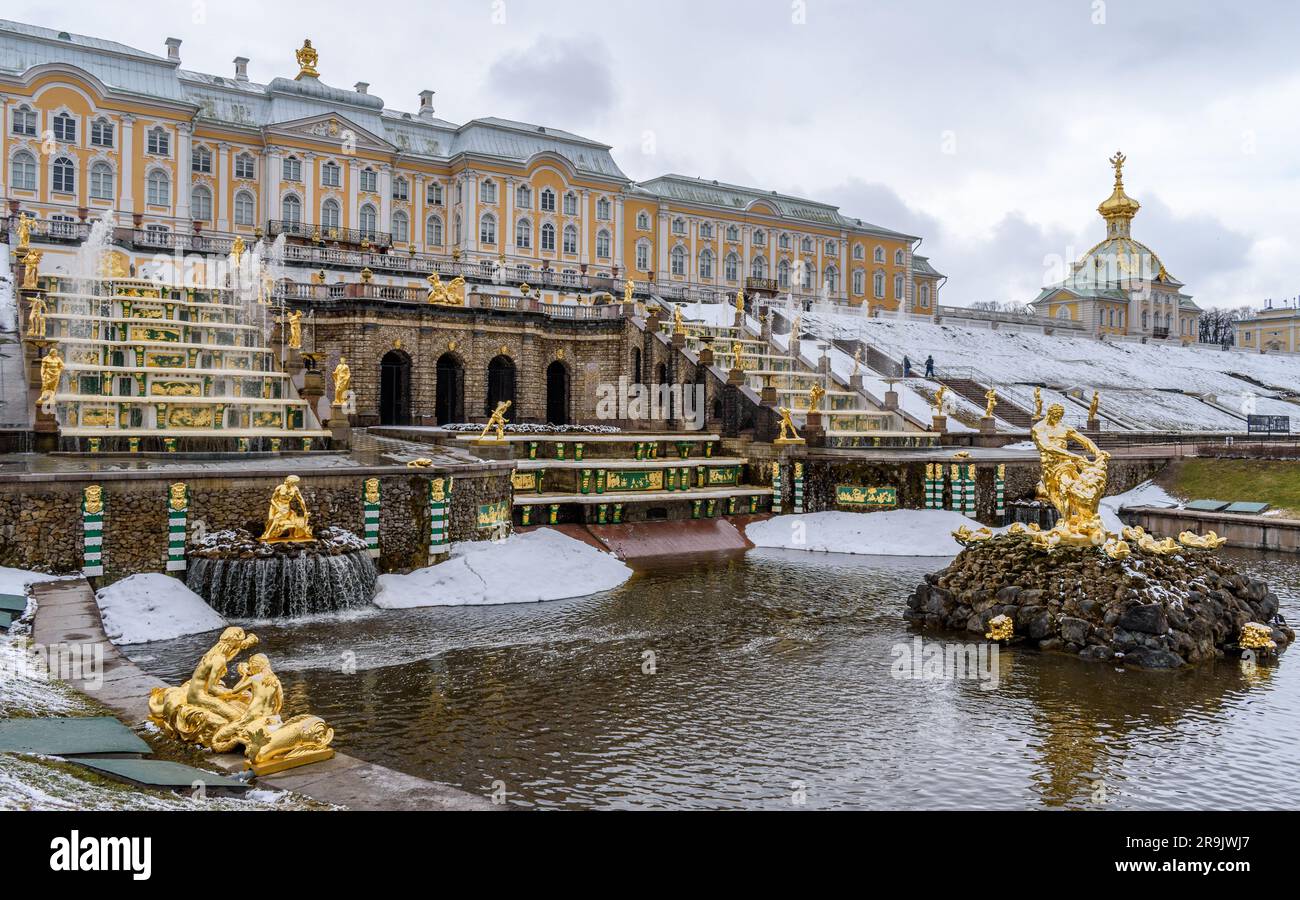 The facade of the Peterhof summer palace of the Romanov Tzars, fountains in the gardens and still clear water, a light snow on topiary bushes. Stock Photo