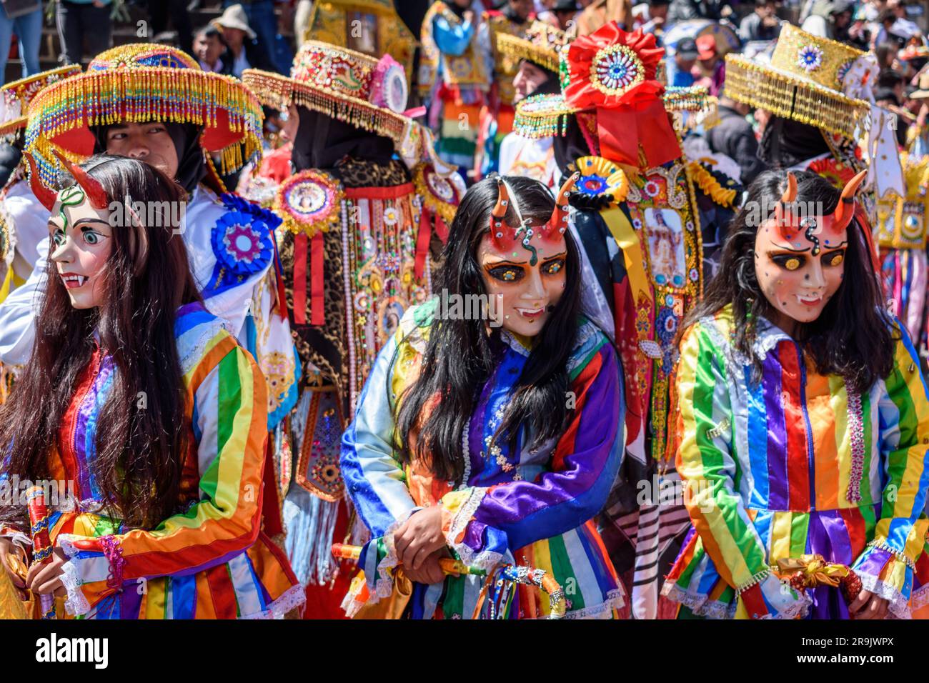 Cusco, a cultural fiesta, people dressed in traditional colourful costumes with masks and hats, brightly coloured streamers. Stock Photo