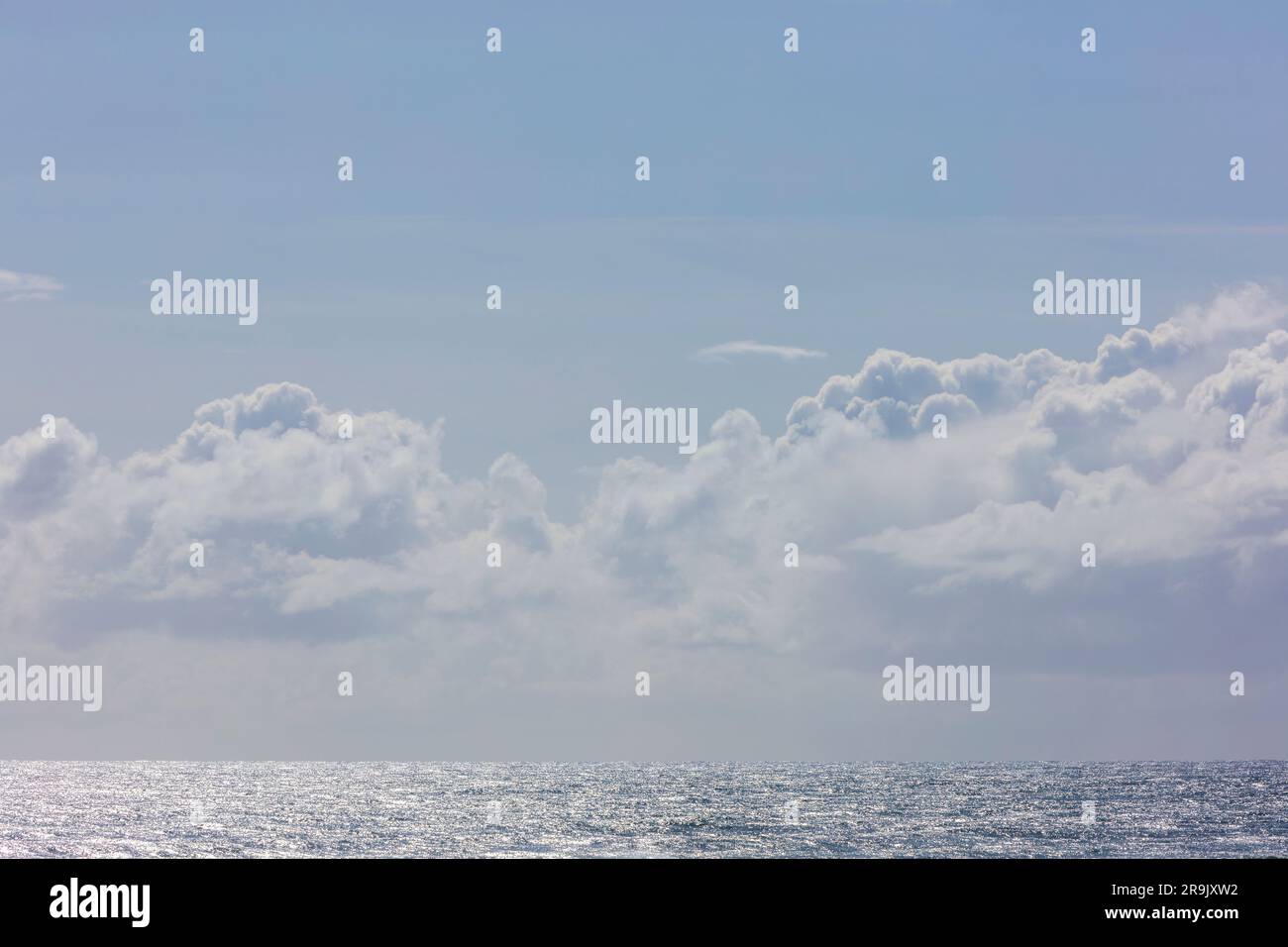 White clouds in a blue sky over the Pacific ocean. Stock Photo