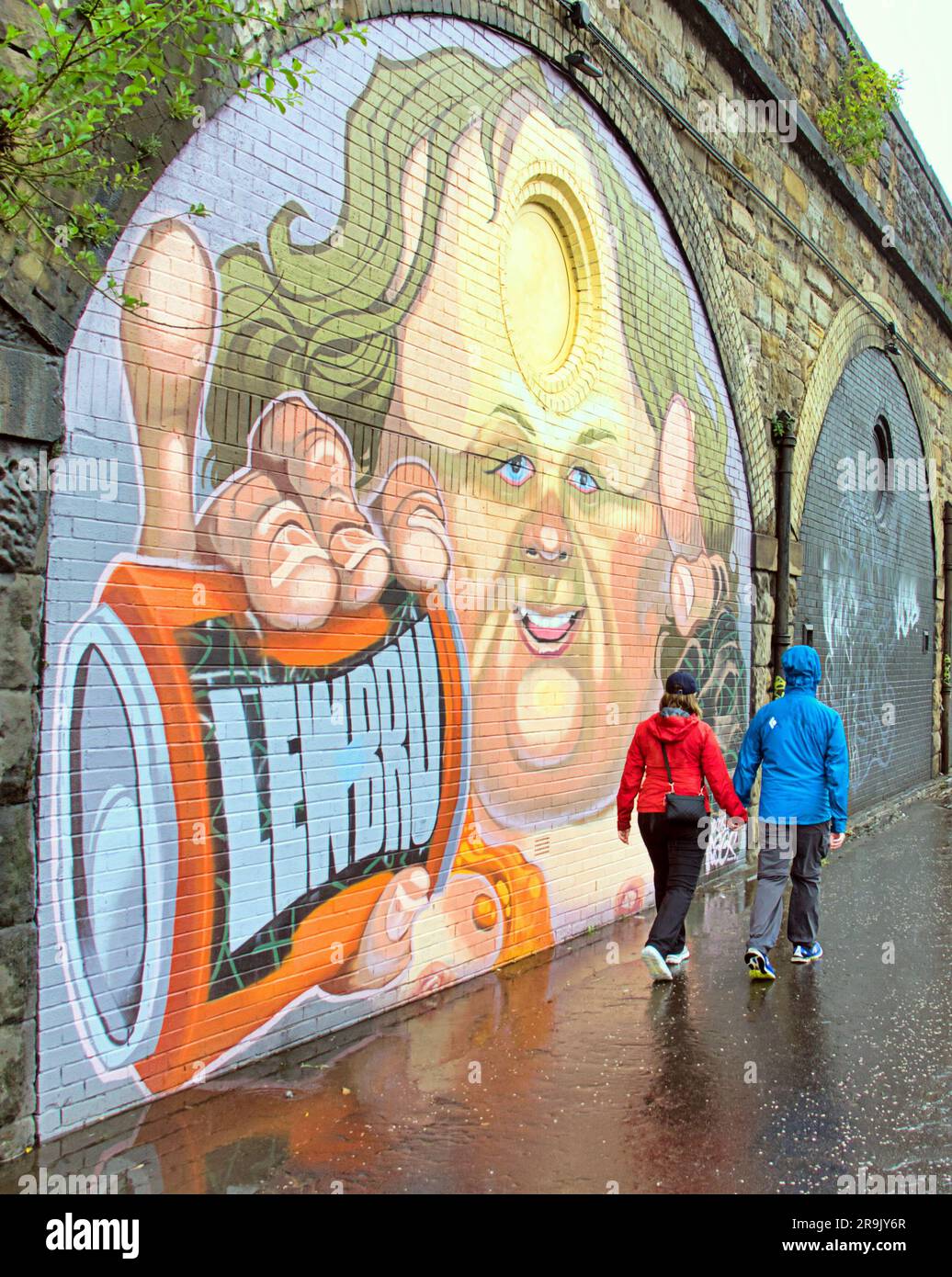 Glasgow, Scotland, UK 27th June, 2023. UK Weather:  Wet in the city as tourists and locals suffer in the rain. The yardwoeks murals on the public path beside the clydeside expressway sum up lewis capaldi and his tourettes and parochial love ov irn bru in the wet weather. Credit Gerard Ferry/Alamy Live News Stock Photo