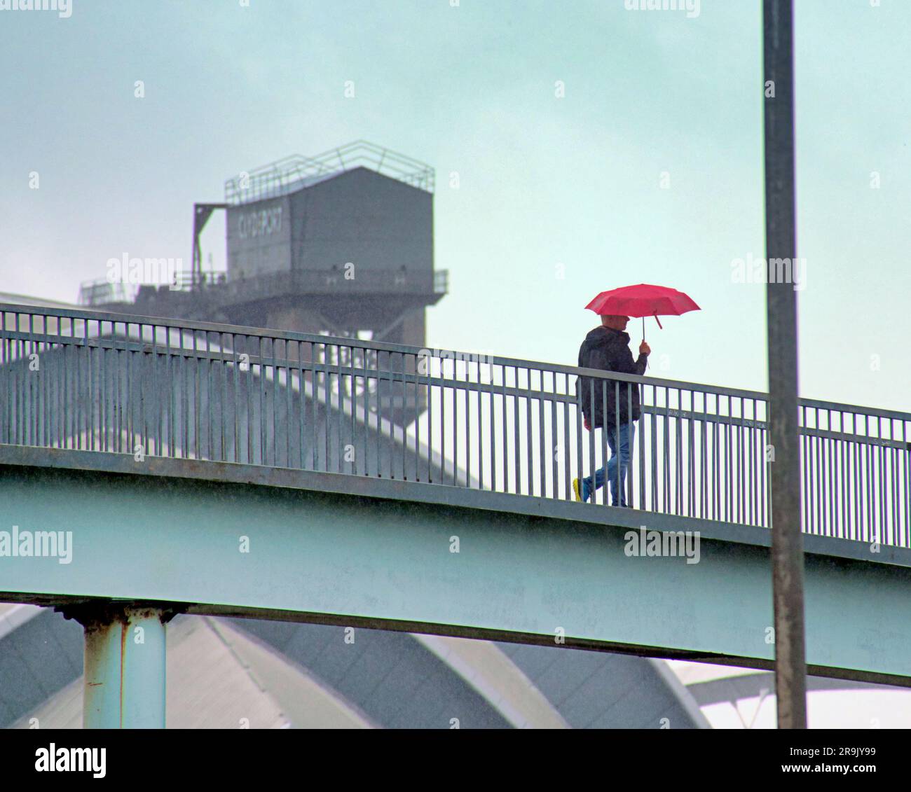 Glasgow, Scotland, UK 27th June, 2023. UK Weather:  Wet in the city as tourists and locals suffer in the rain. The winchman's house at the top of the finnieston crane in the background high in the sky on the footbridge across the clyde expressway.  Credit Gerard Ferry/Alamy Live News Stock Photo
