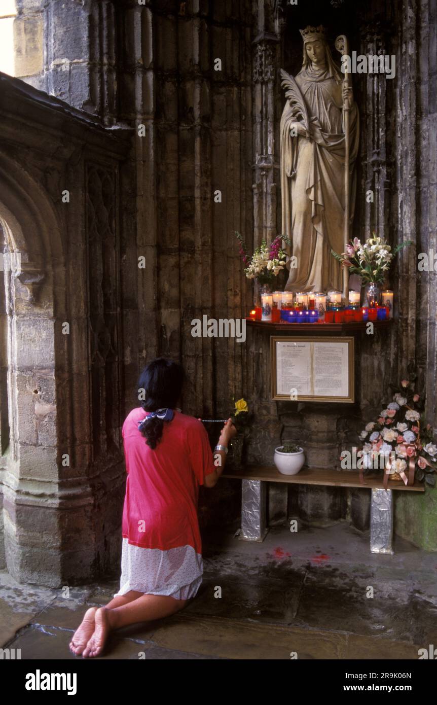 Saint Winefrides Shrine, Holywell, Wales.  Roman Catholic annually gather on the feast day at St Winefride at her  shrine on 22 June. A pilgrim knees at the foot and holds her rosary beads and prays to St Winefride. Holywell, Flintshire Wales, UK 1990s. HOMER SYKES Stock Photo