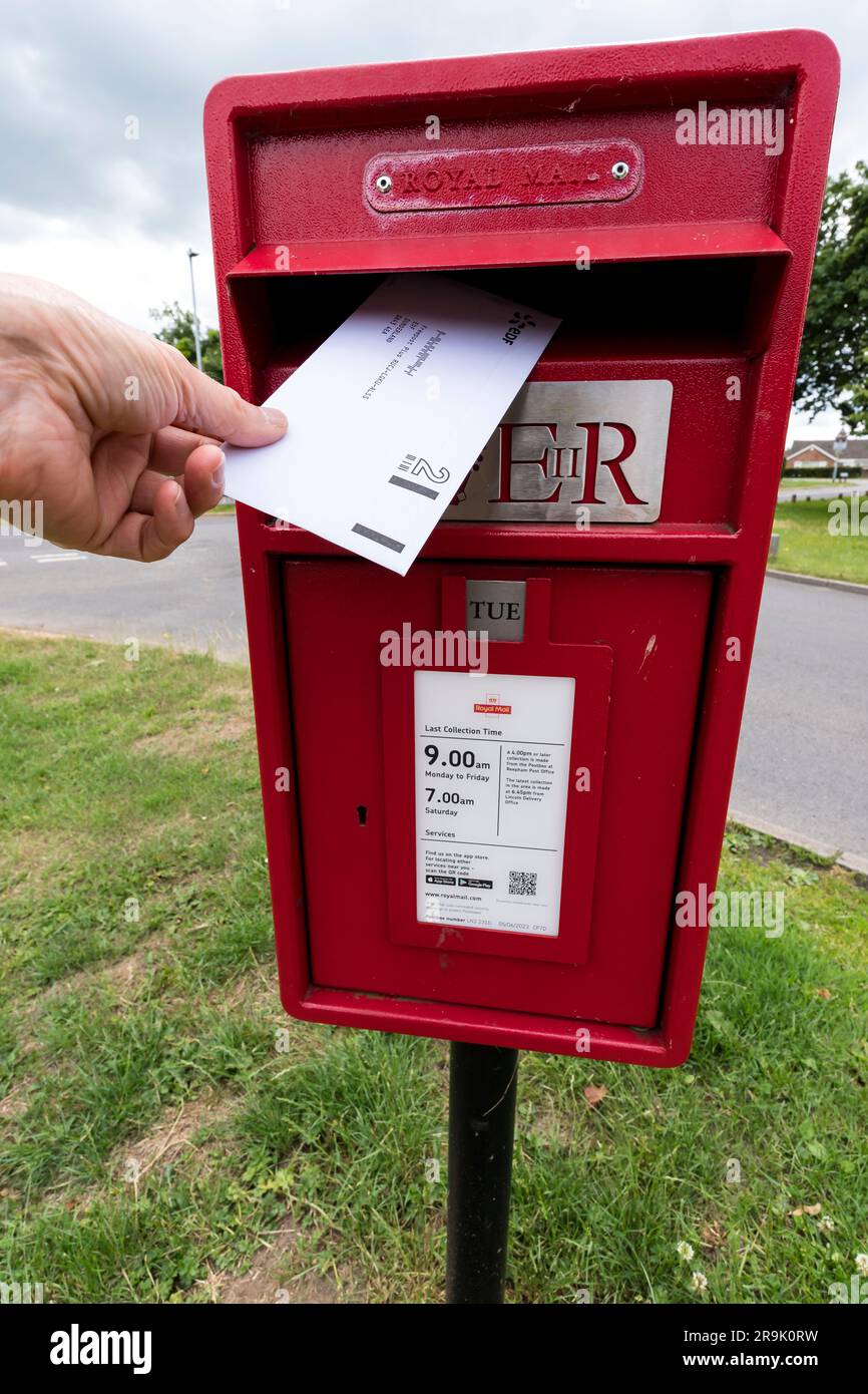 Posting letter in pillar mounted Royal Mail post box Stock Photo Alamy