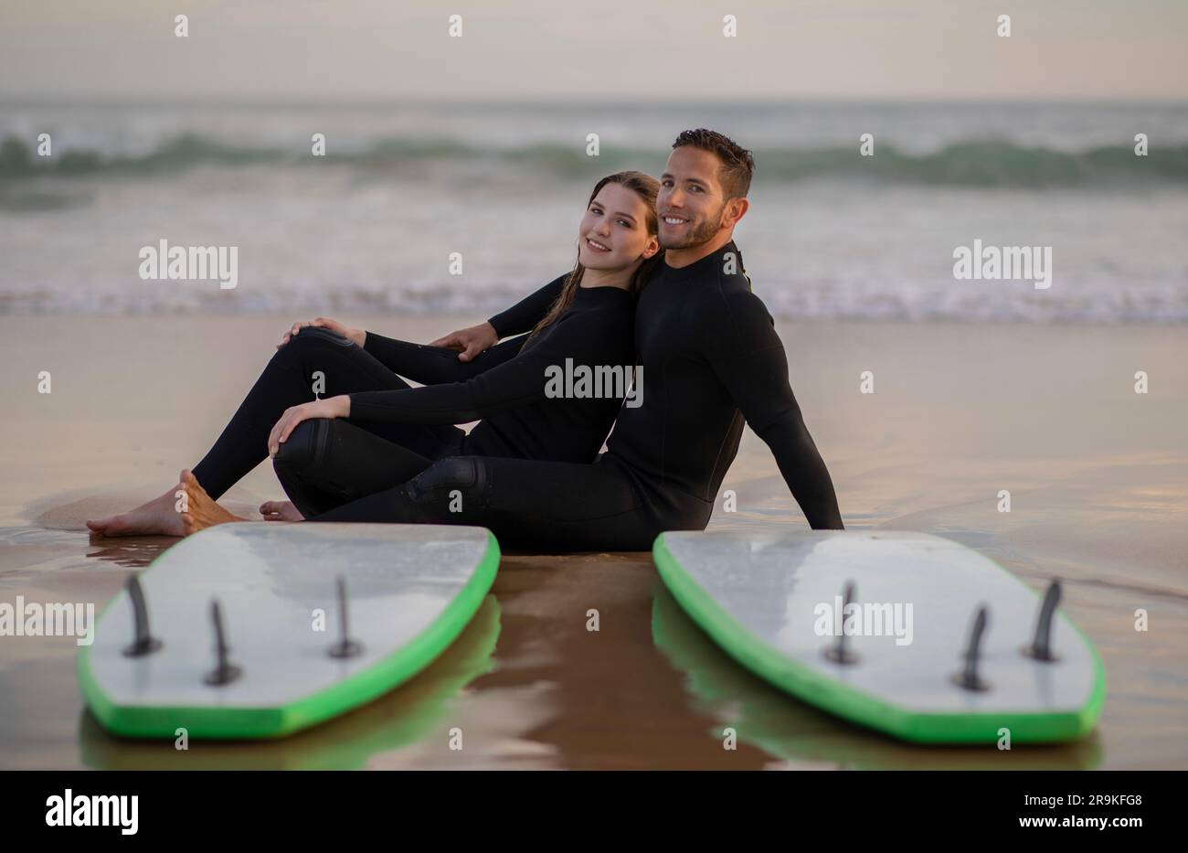 Romantic Young Couple Wearing Wetsuits Posing With Surfboards On The