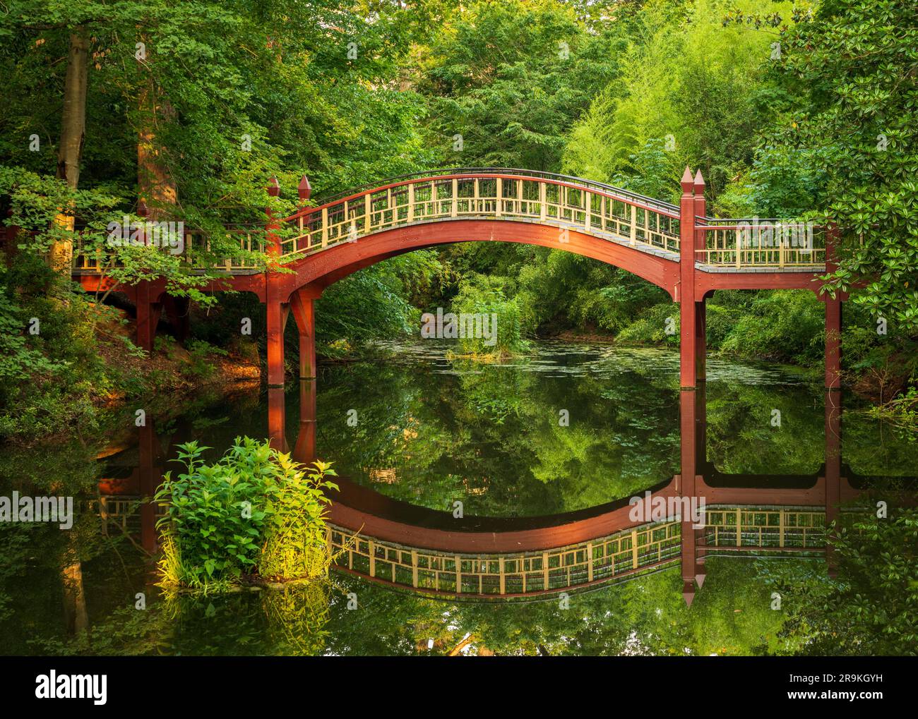 Ornate wooden bridge over very calm Crim Dell pond on campus of William and Mary college in Williamsburg Virginia Stock Photo