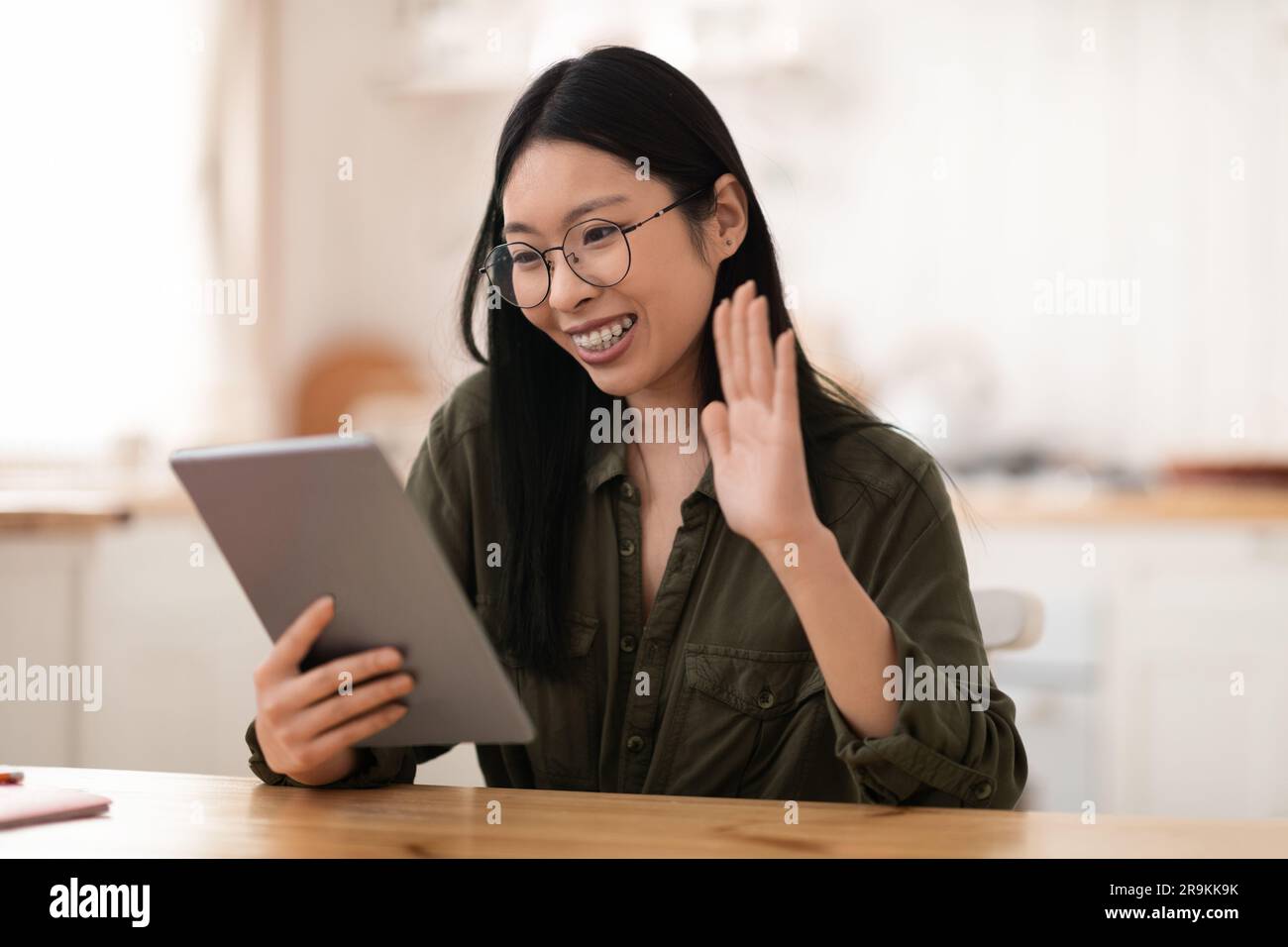 Cheerful young chinese woman using digital tablet at kitchen Stock Photo