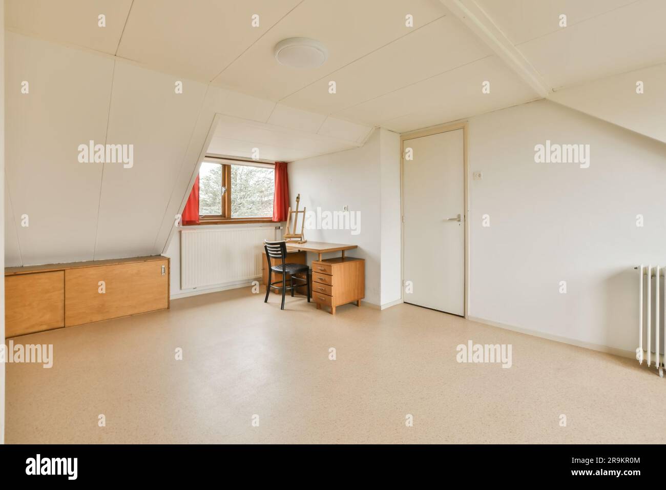 an empty room with a desk, chair and rad in the corner on the left is a ...