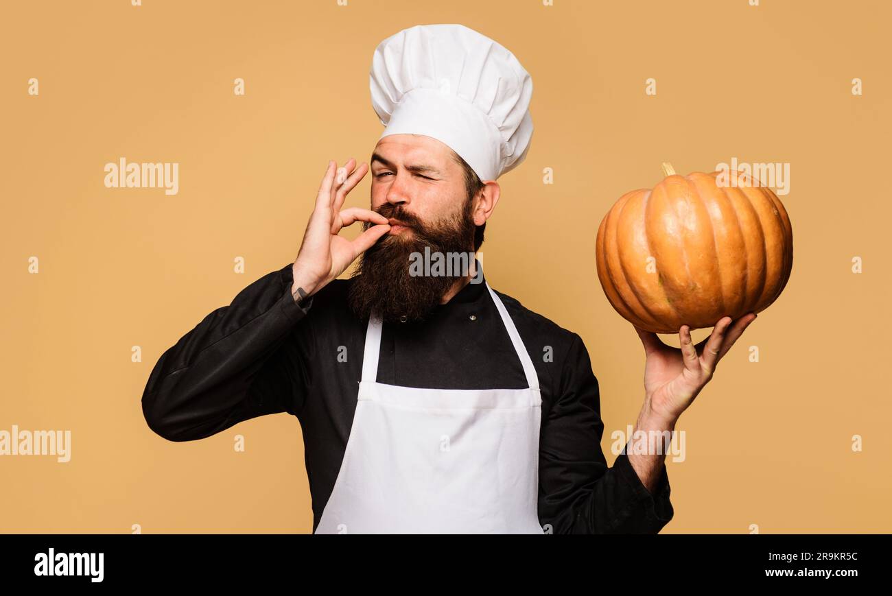 Male chef with pumpkin showing sign ok. Bearded man in chef uniform with pumpkin. Organic food. Healthy product. Harvest festival. Thanksgiving Stock Photo
