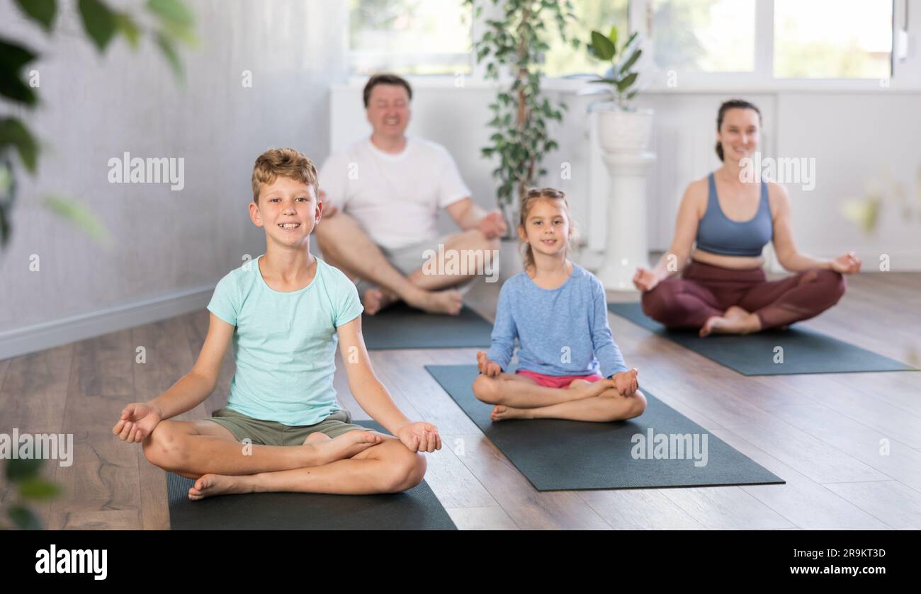 Teenage girl with her parents practices yoga in lotus position Stock ...