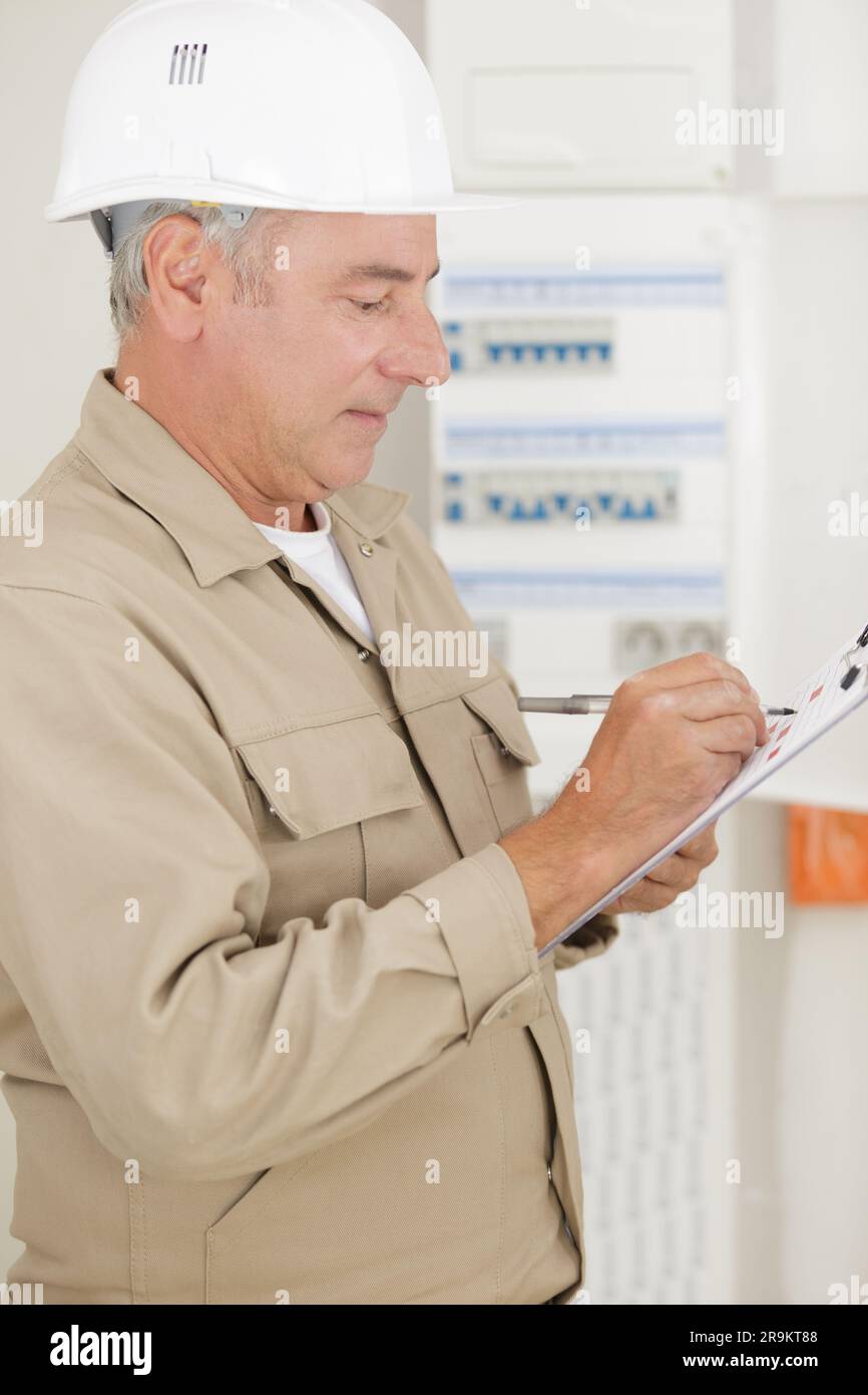 senior tradesman writing on clipboard Stock Photo