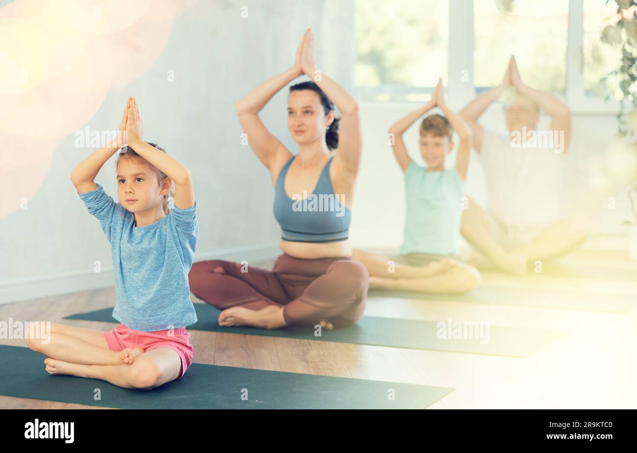 Mom with her family practices yoga in lotus position Stock Photo - Alamy