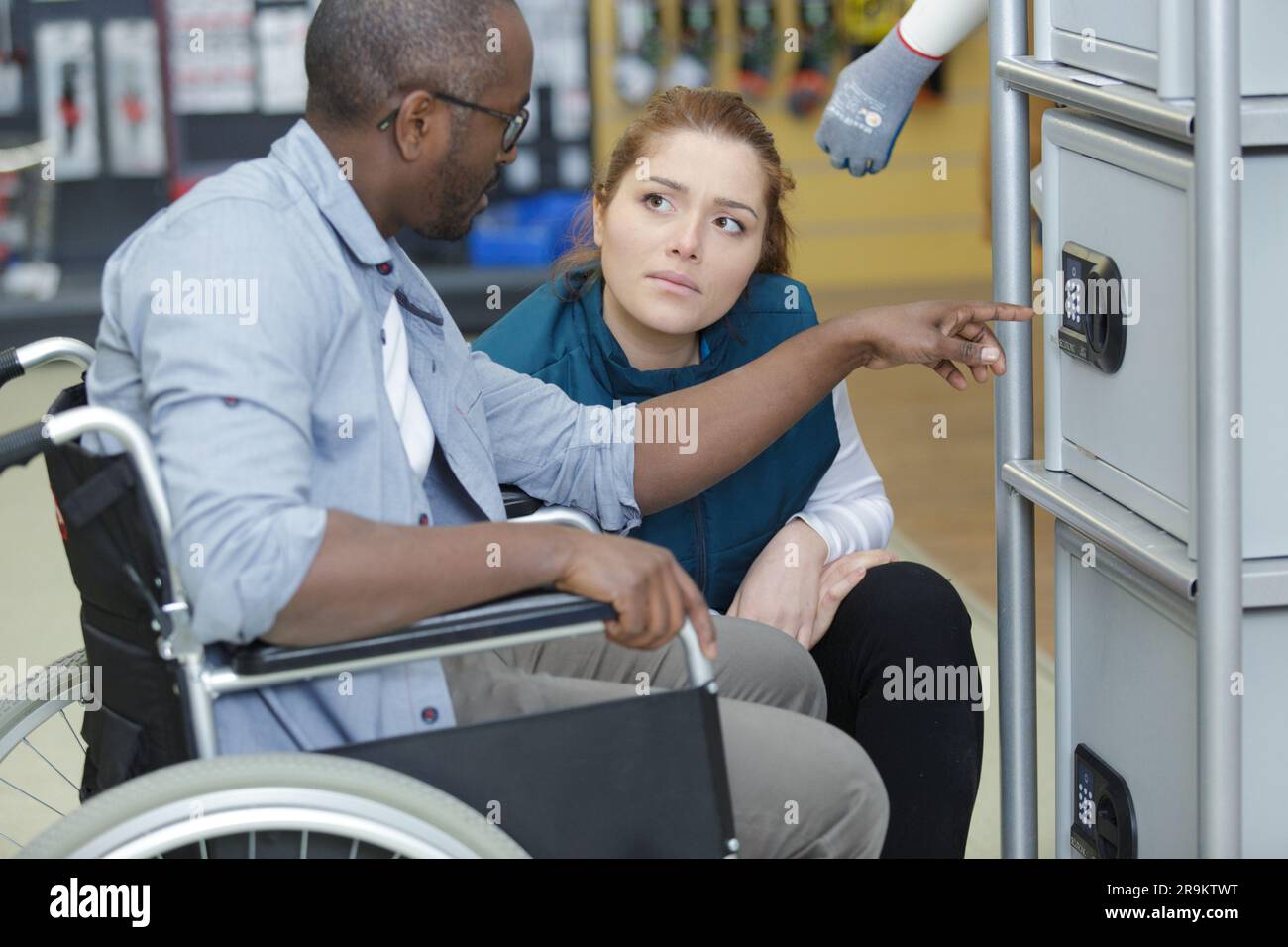 hardware store clerk assists male customer in wheelchair Stock Photo