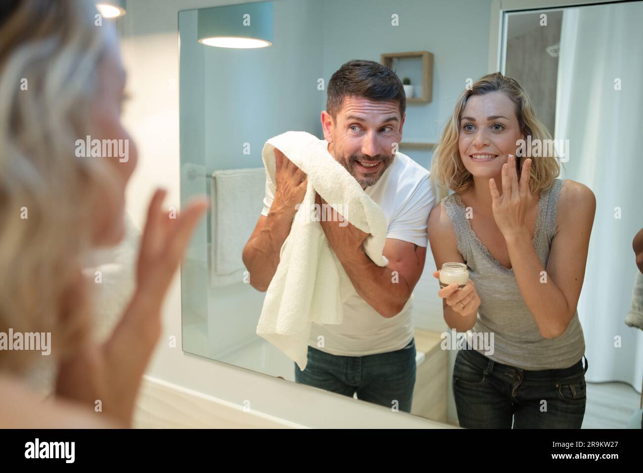 couple doing their ablutions looking in the bathroom mirror Stock Photo