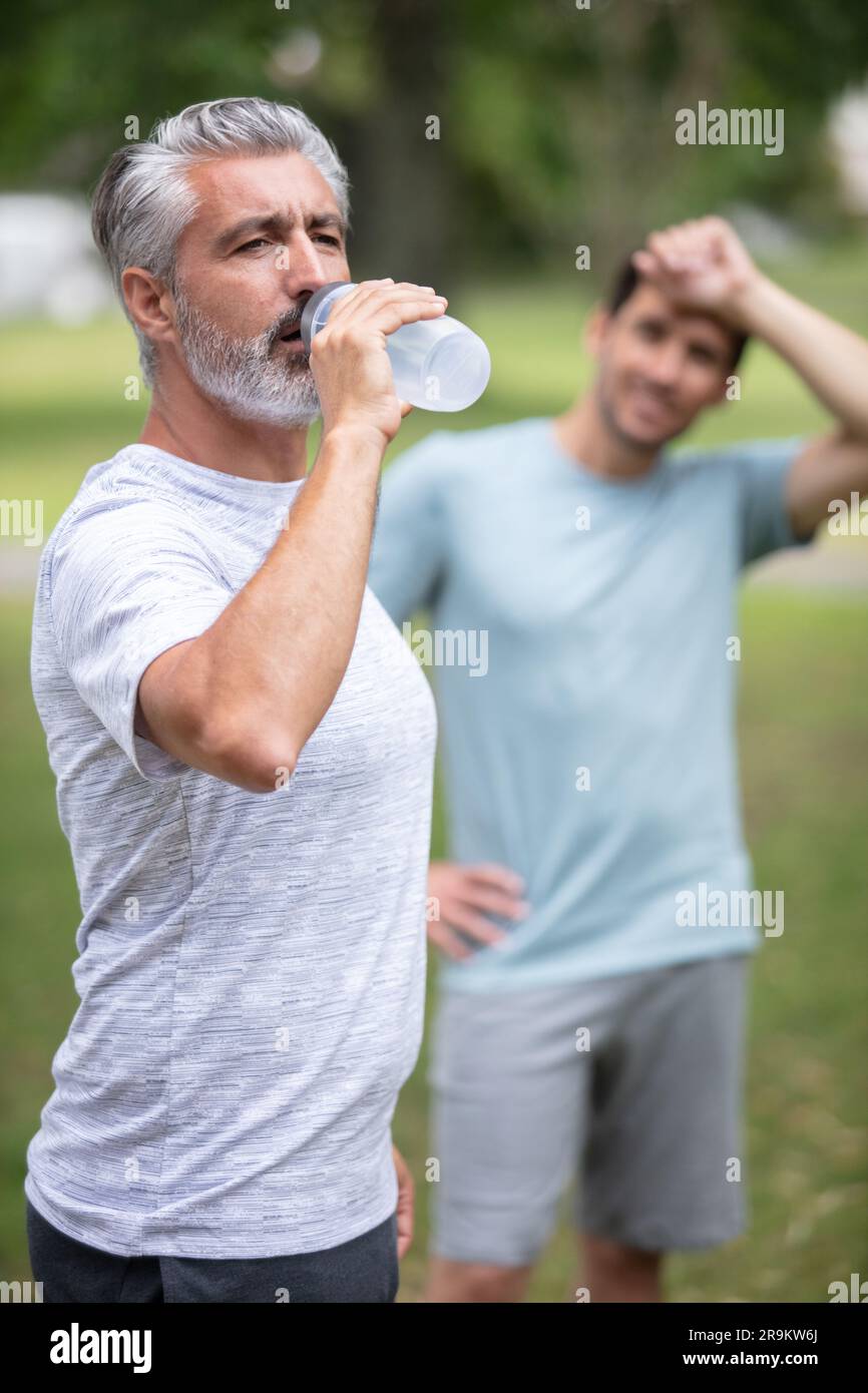 two guys drinking water while working out and running Stock Photo Alamy