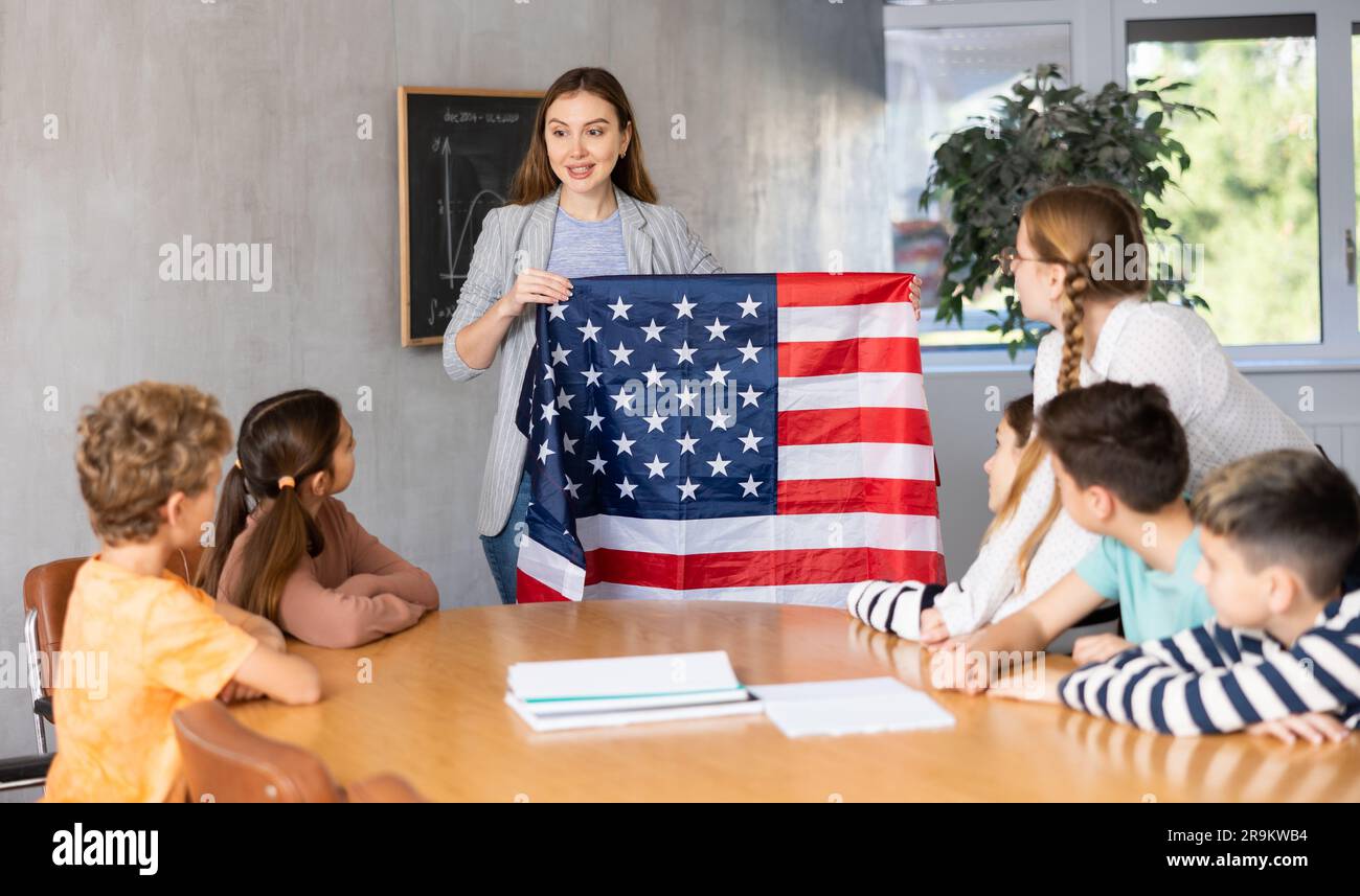 Geography lesson in school class - teacher talks about United States of America, holding flag in his hands Stock Photo