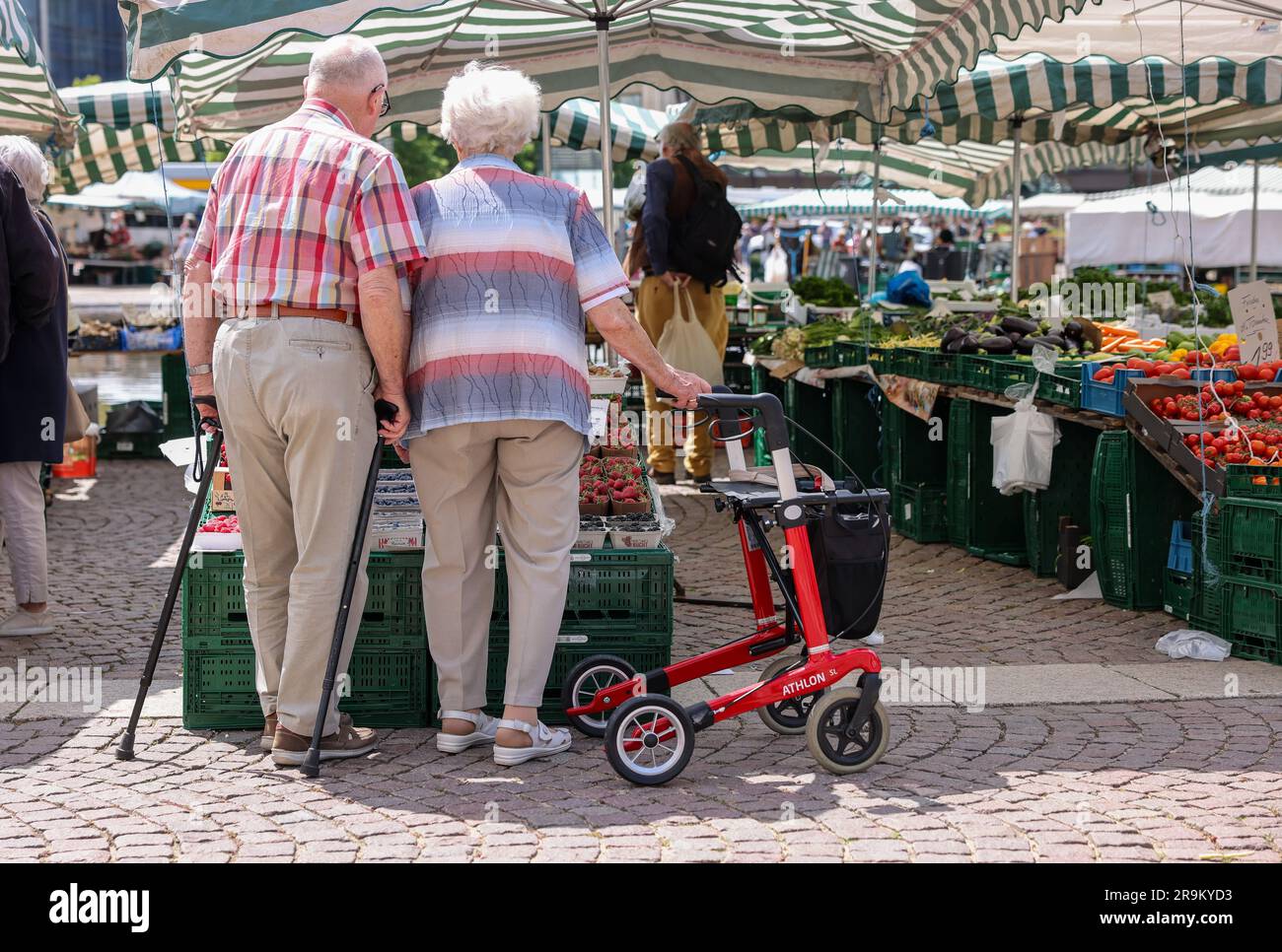 Leipzig, Germany. 27th June, 2023. Two senior citizens stand with walkers and rollators at the weekly market in downtown Leipzig. The approximately 21 million pensioners in the country will receive more money starting in July. With the annual pension adjustment, retirement benefits will rise by 4.39 percent in the west and 5.86 percent in the east. In addition, almost 30 years after reunification, the so-called pension value in the east will be brought into line with that in the west - one year earlier than planned. Credit: Jan Woitas/dpa/Alamy Live News Stock Photo
